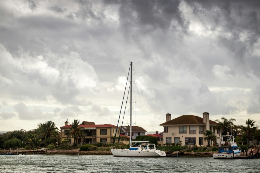 white boat on body of water near brown concrete building under white clouds during daytime