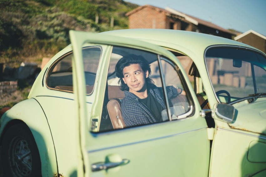 man in black crew neck shirt in green volkswagen beetle