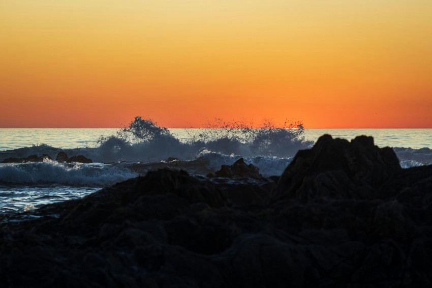 the sun is setting over the ocean with waves