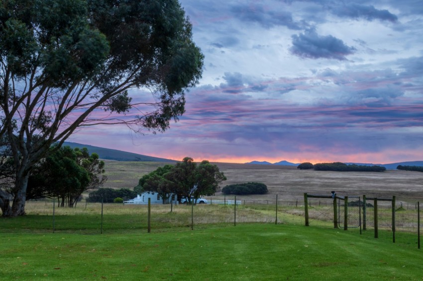 a fenced in field with a body of water in the background