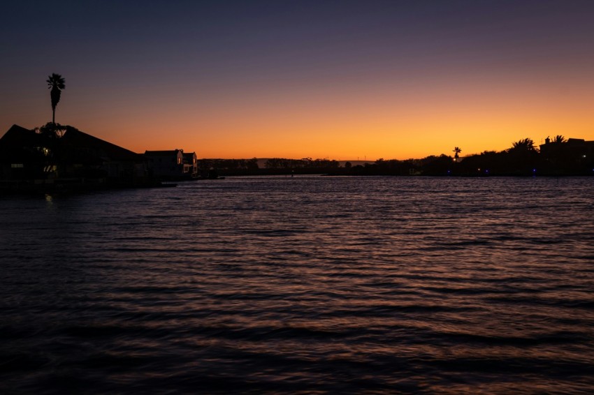 silhouette of building near body of water during sunset