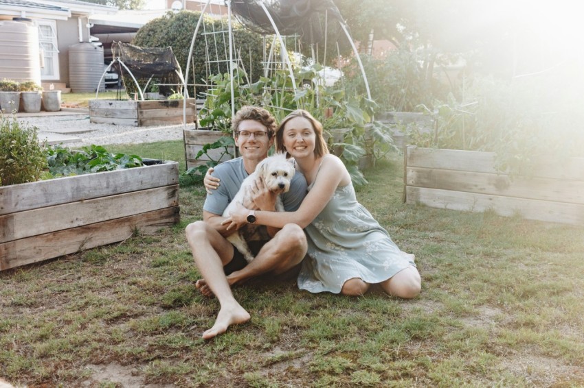 woman in gray tank top sitting on brown wooden bench beside white short coated dog