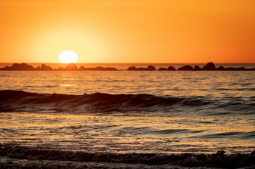 the sun is setting over the ocean with waves