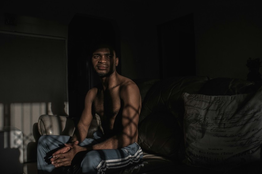 topless man sitting on black and white textile mIed