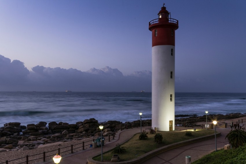 white and red lighthouse near ocean during daytime