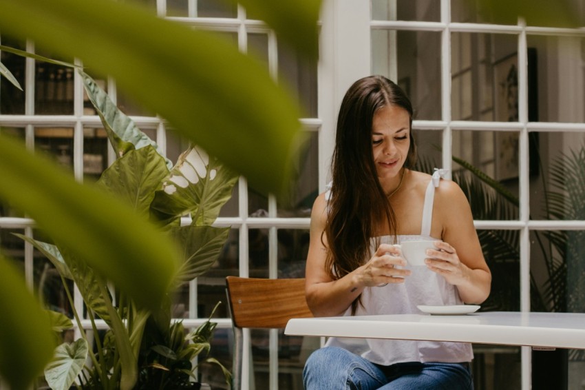 a woman sitting at a table looking at her phone