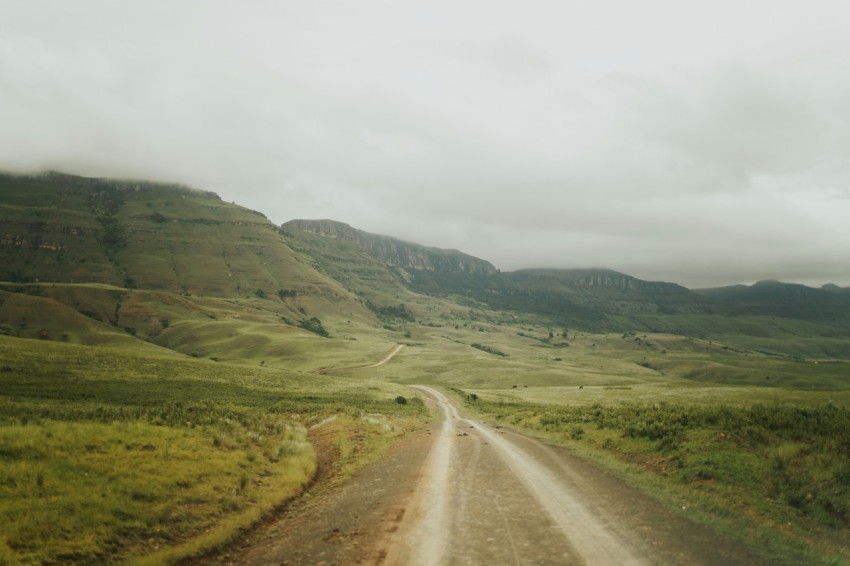 a dirt road in the middle of a lush green valley