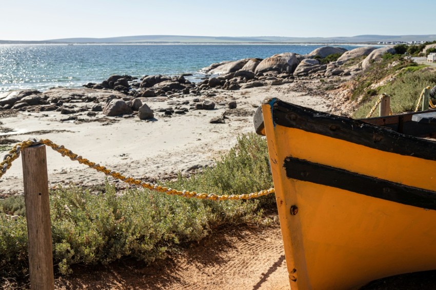 a yellow boat sitting on top of a sandy beach