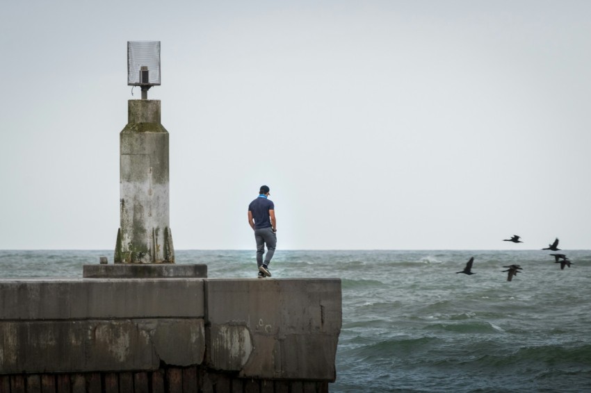 man in blue jacket standing on gray concrete dock during daytime