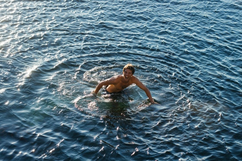 topless man swimming in body of water