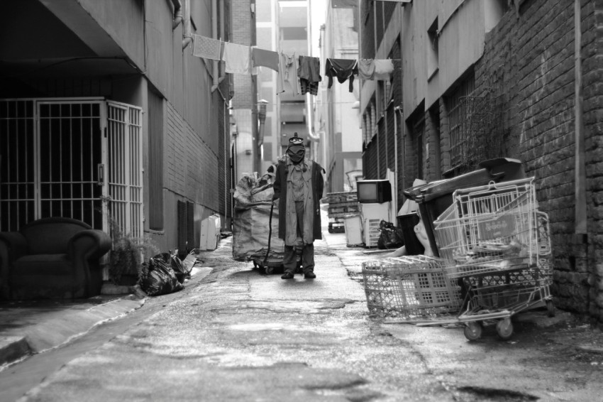 grayscale photography of man pulling cart in the middle of road