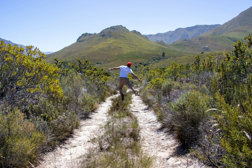 a man riding a skateboard down a dirt road