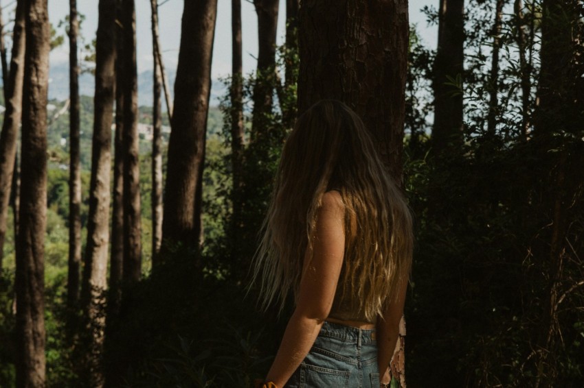 woman in blue denim shorts standing near brown tree during daytime KcoHEJ7K