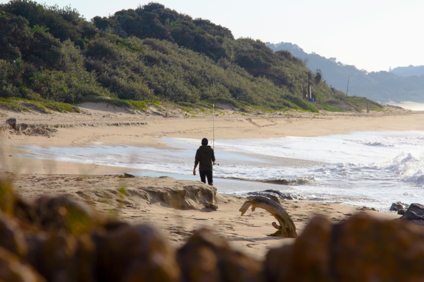 man in black jacket walking on beach during daytime