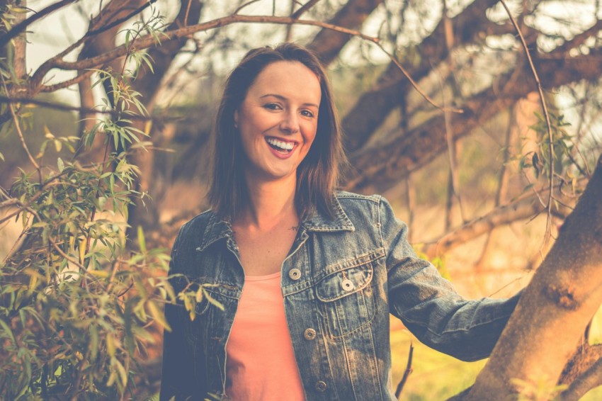 woman wearing blue denim jacket behind of tree CFH8x