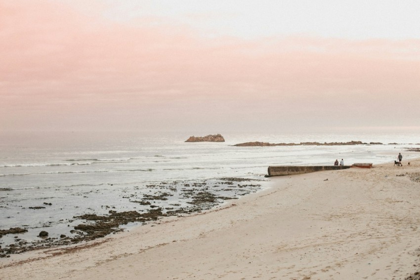 a couple of people standing on top of a sandy beach