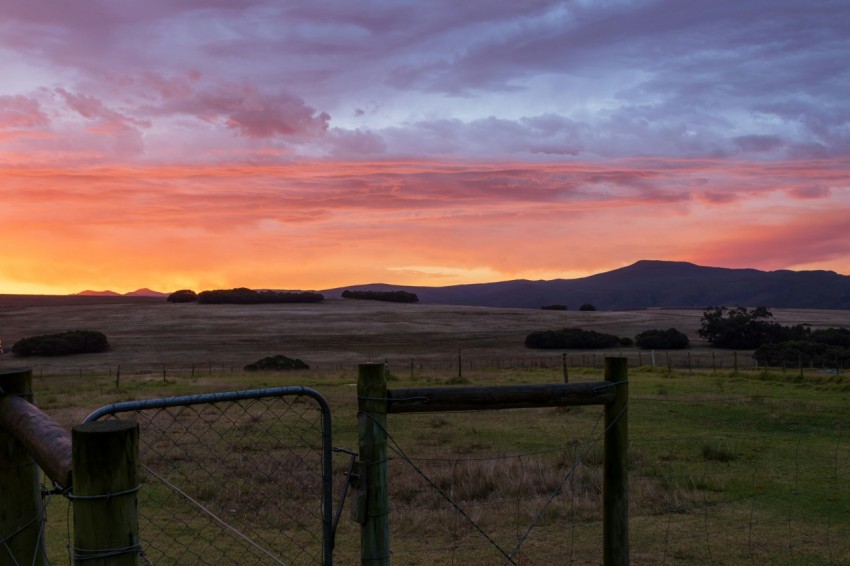 a field with a fence and a sunset