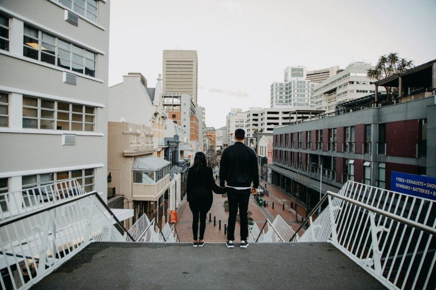 a man and woman walking on a bridge over a city