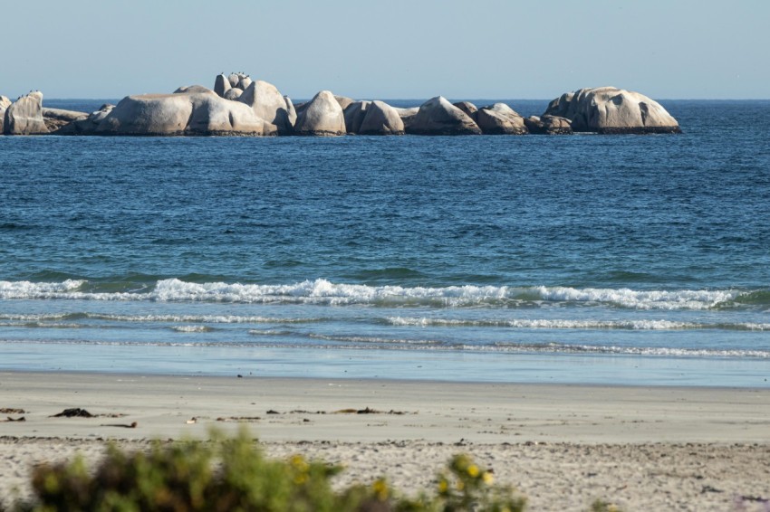 a group of rocks sitting on top of a beach next to the ocean