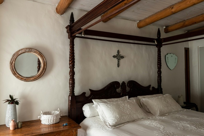 a bedroom with a bed dresser mirror and cross on the wall