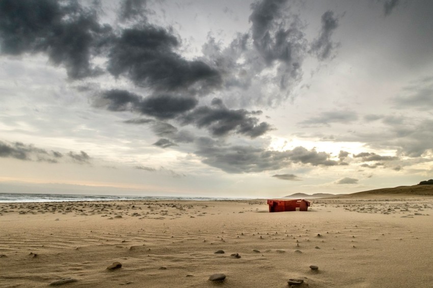 a cloudy sky over a beach with a boat in the distance