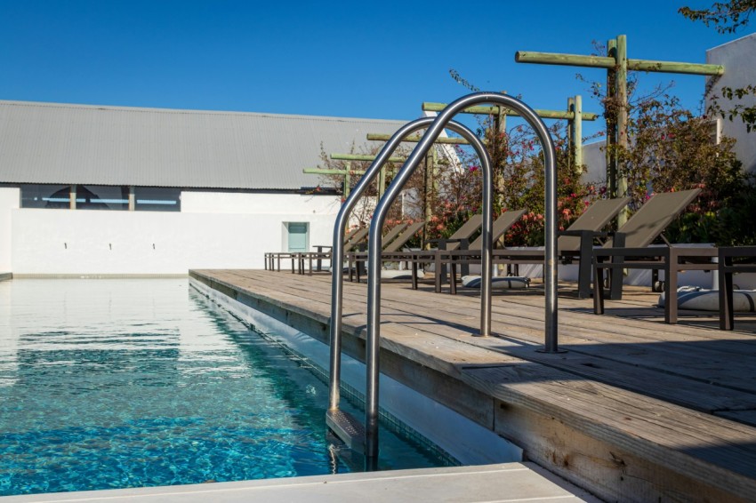 a swimming pool with a wooden deck and chairs around it