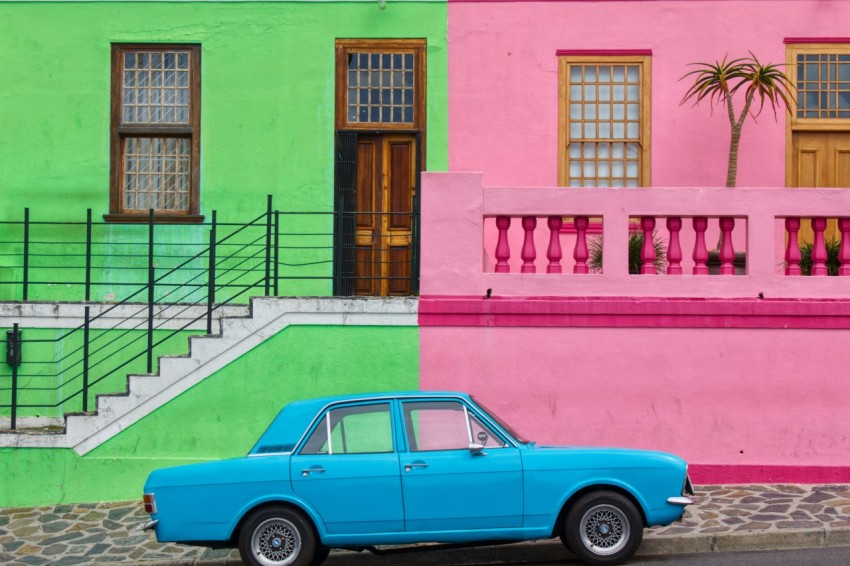 blue sedan parked beside pink and green house HSyuQXl