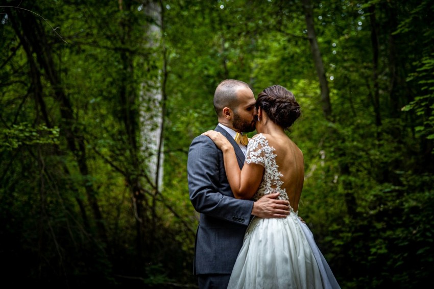 man in black suit kissing woman in white wedding dress