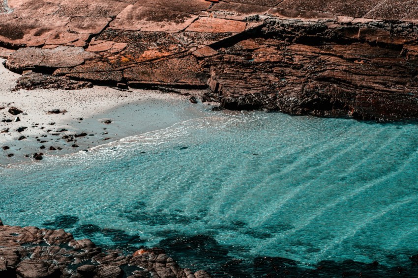 brown rocky mountain beside body of water during daytime