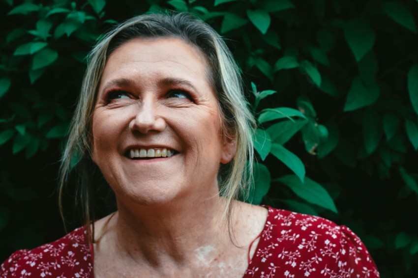 a woman smiling in front of a bush