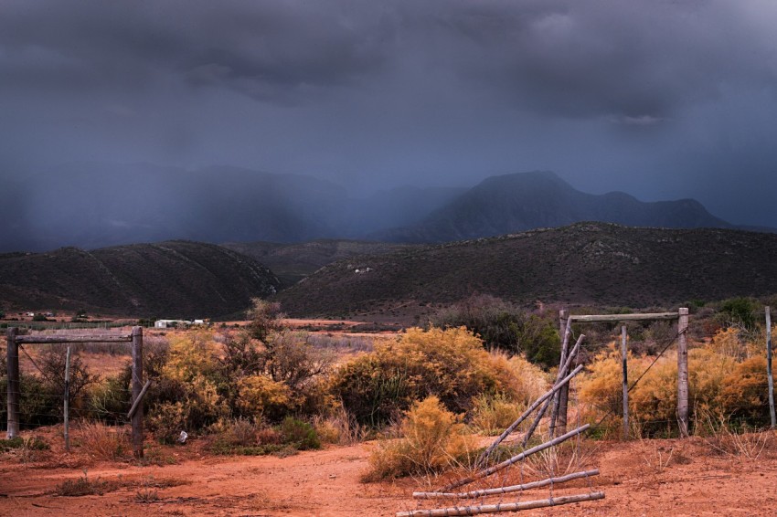 a wooden gate sitting in the middle of a dirt field