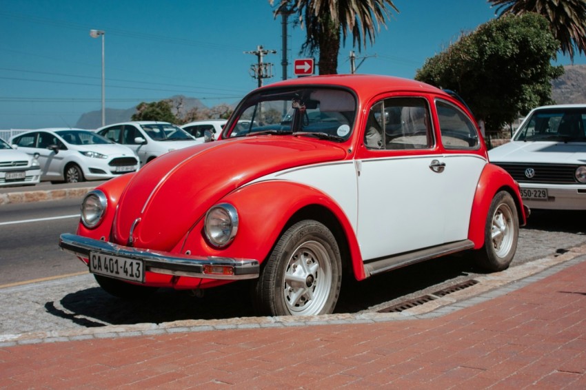 red and white volkswagen beetle parked on side of road fl7Tn