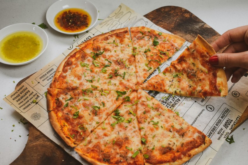 a person holding a slice of pizza on top of a piece of paper