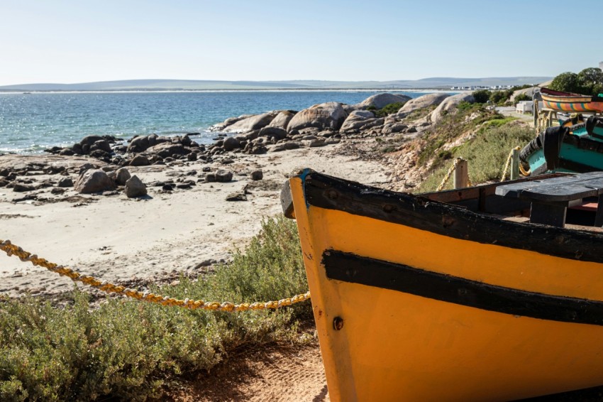 a yellow boat sitting on top of a sandy beach