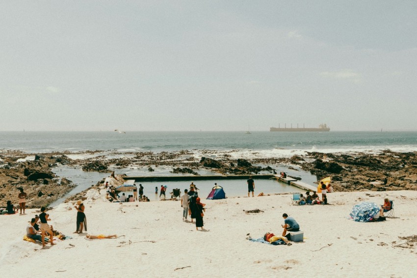 a group of people standing on top of a sandy beach j5oPBGxnl