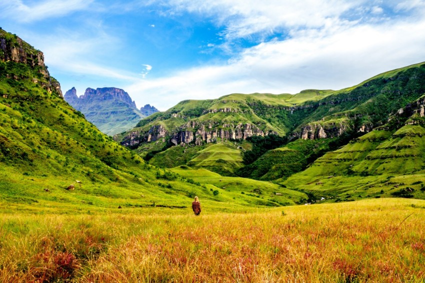 green and beige grass field surrounded with mountains under blue sky