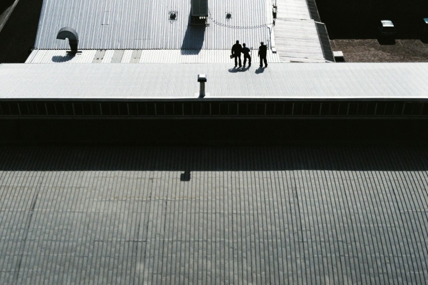 three men standing on gray pavement