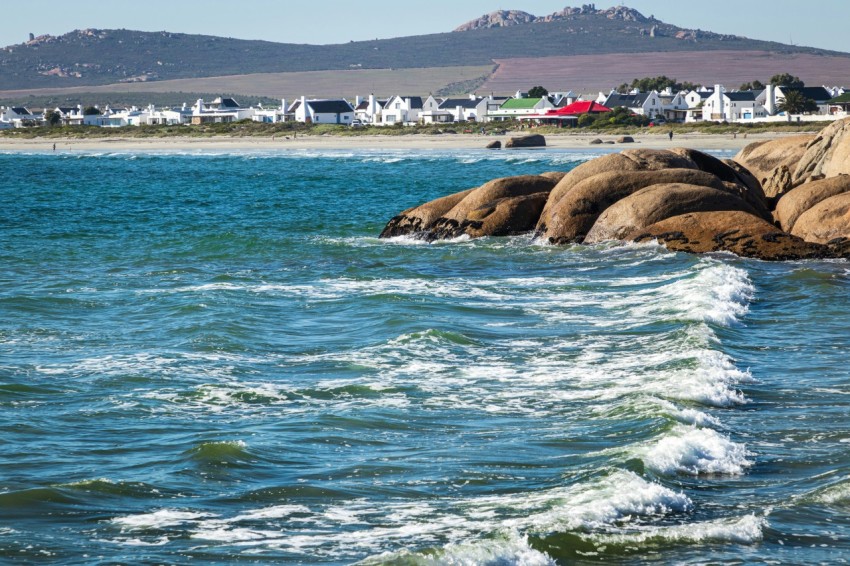 a body of water with rocks and houses in the background mV