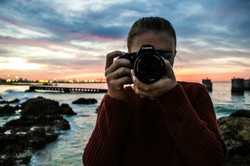 photo of woman holding black canon dslr camera near body of water 4GpD1oP