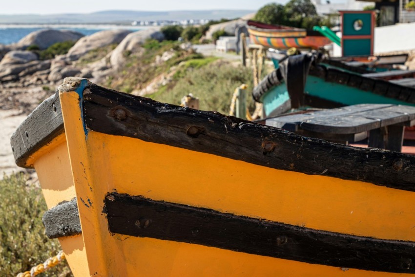 a yellow boat sitting on top of a sandy beach