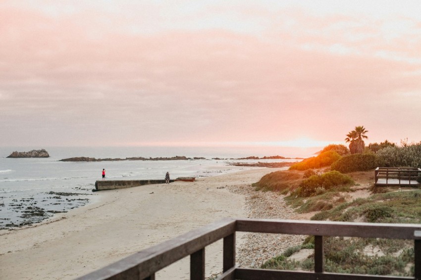 a bench sitting on top of a beach next to the ocean