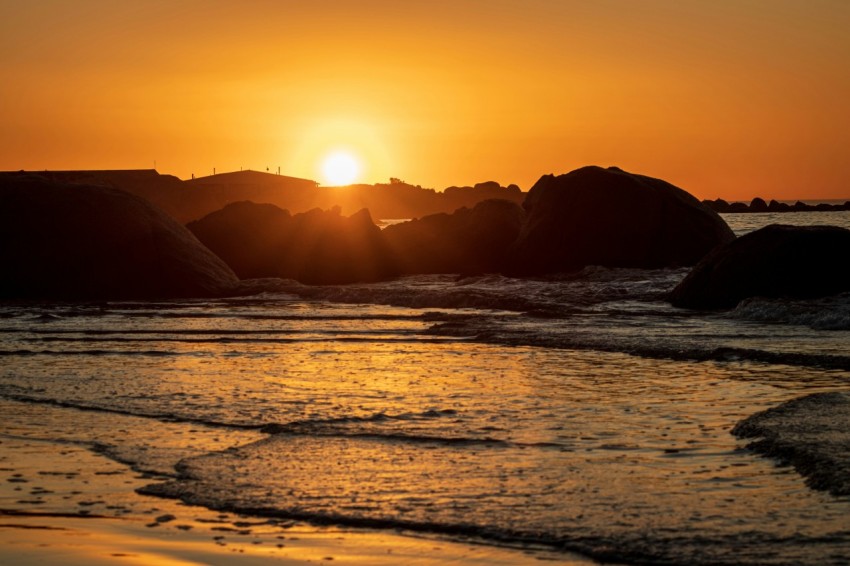 the sun is setting over the water at the beach