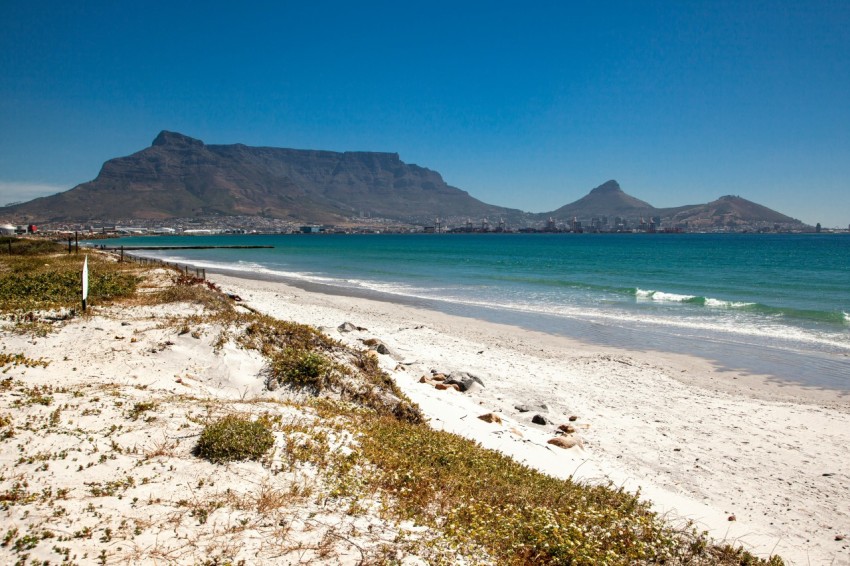 a beach with a body of water and mountains in the background