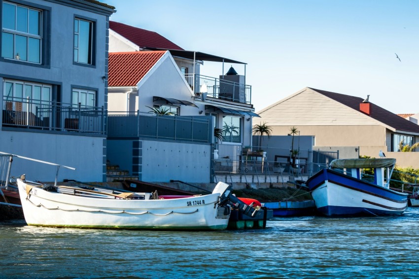 white and blue boat on water near white concrete building during daytime 7H0bj6UUU