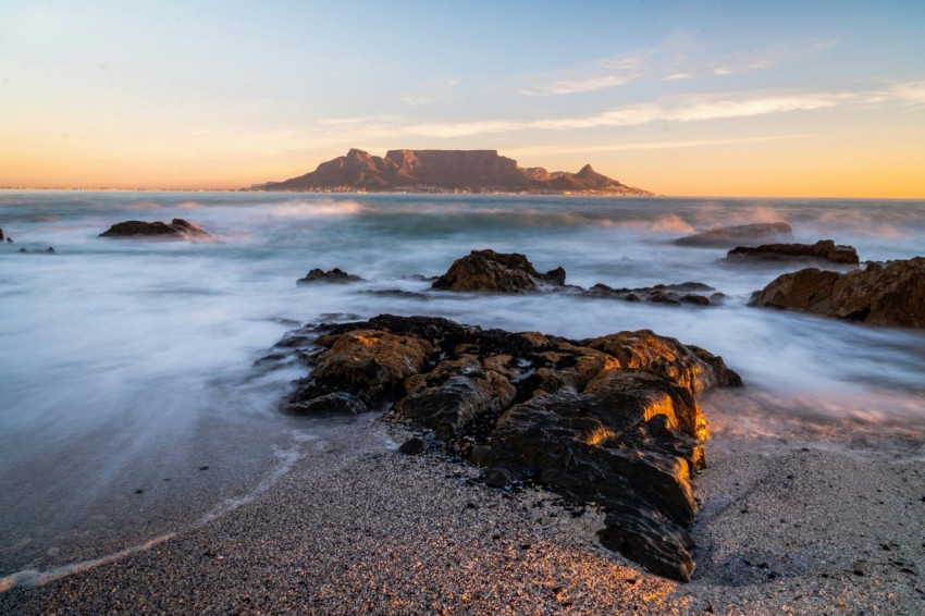 water splashing on shore rocks overlooking island at the horizon