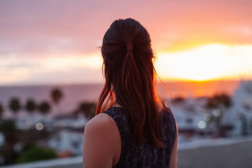 a woman standing on top of a roof looking at the sunset e4