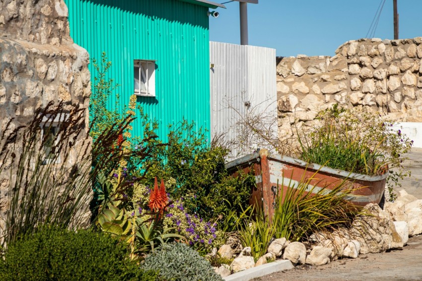 a small green building sitting next to a rock wall