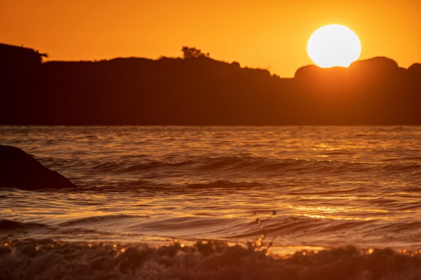 the sun is setting over the ocean with waves