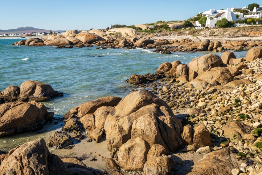 a rocky shore line with houses in the distance dInh