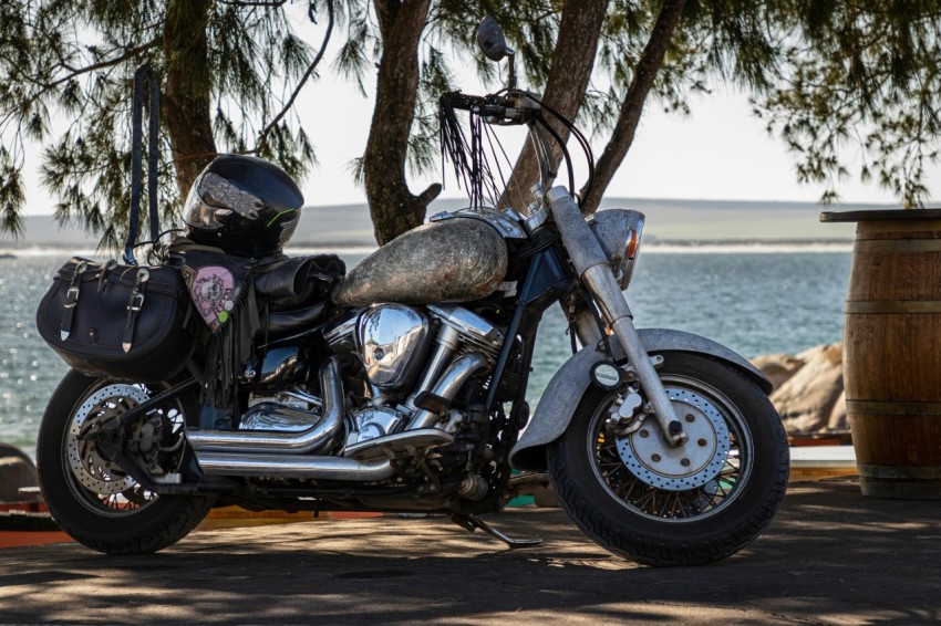 a motorcycle parked next to a tree near the water CcnqYqTg